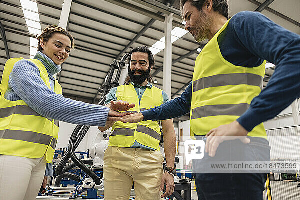 Happy engineers stacking hands in factory