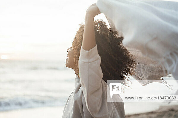 Glückliche junge Frau mit Schal am Strand