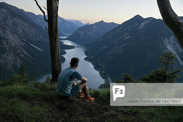 Sportler bewundern Bergkette und See bei Sonnenuntergang