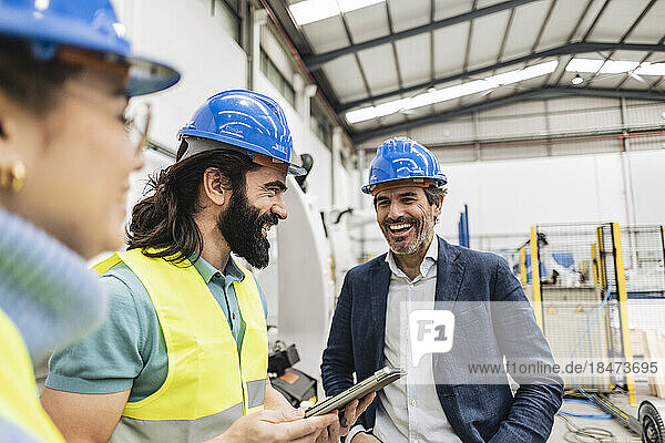 Happy engineer with colleagues standing in factory