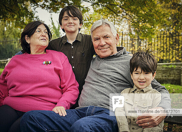 Lächelnde Enkel sitzen mit Großeltern im Park