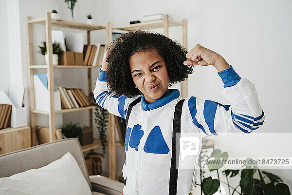 Girl wearing space suit flexing muscle at home
