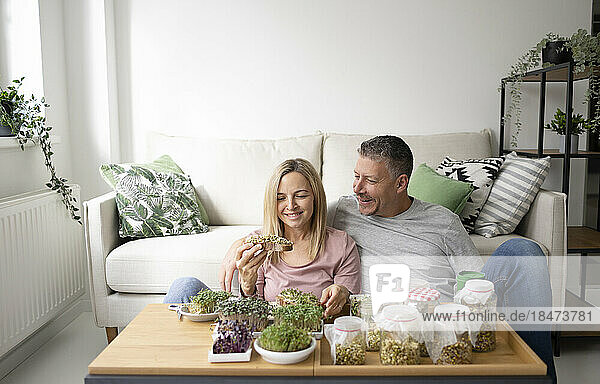Couple with sprouts on toasted bread sitting at home