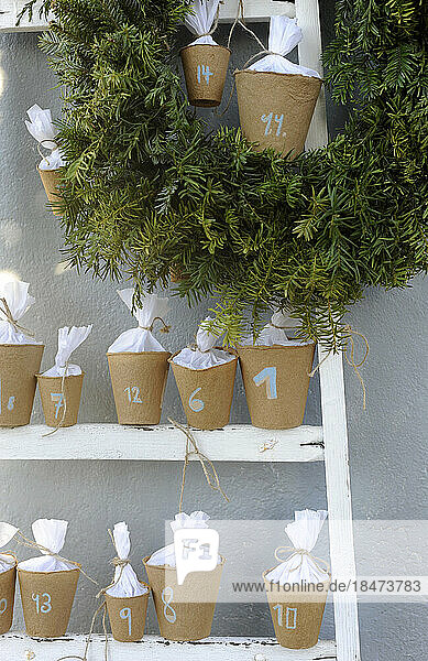 DIY advent calendar made of upcycled flower pots standing on ladder steps