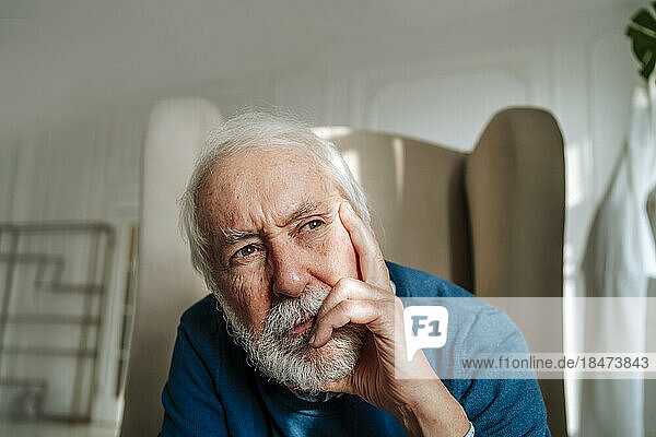 Thoughtful senior man with gray hair sitting at home
