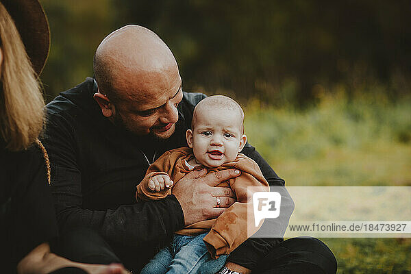Bald man sitting with cute baby daughter