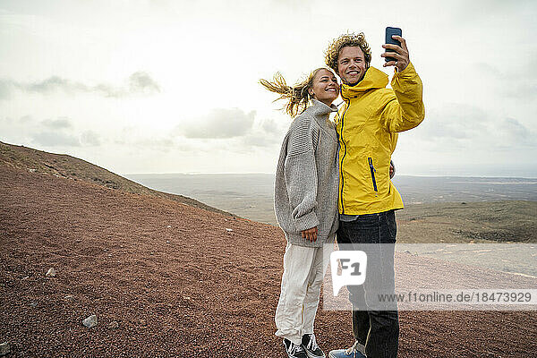 Glückliches Paar macht ein Selfie mit dem Smartphone  das auf dem Berg steht