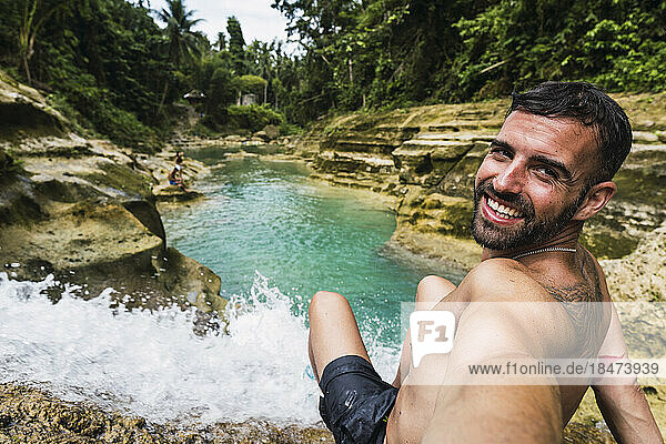Glücklicher Mann  der ein Selfie am Wasserfall macht