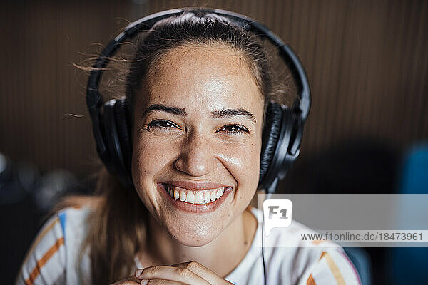 Happy young podcaster wearing headphones in studio