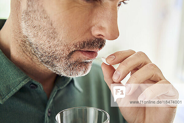 Close-up of adult man taking pill