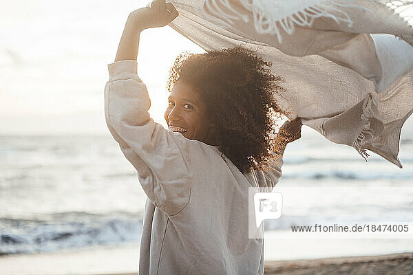 Fröhliche junge Frau mit Schal am Strand