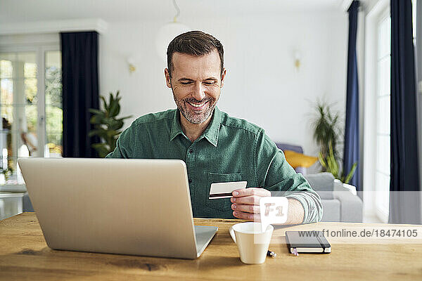 Man paying with credit card on his laptop sitting at desk