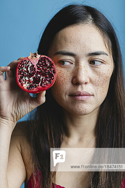 Woman holding pomegranate against blue background