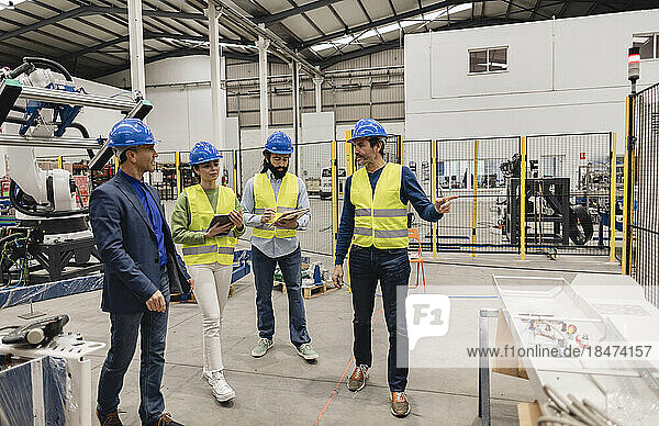 Engineers wearing hardhats discussing in robotics factory