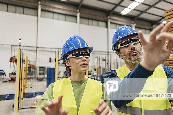 Mature engineer with colleague gesturing in factory