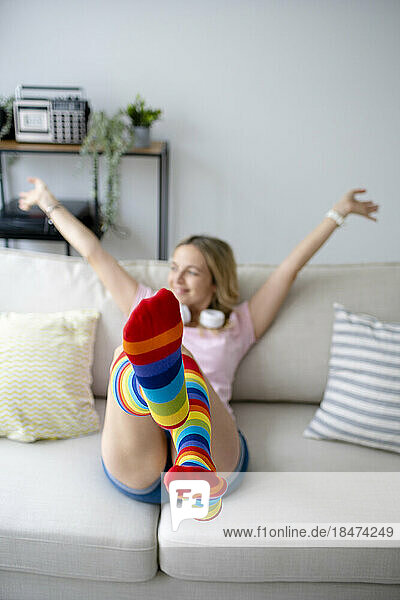 Woman wearing rainbow stockings enjoying on sofa at home