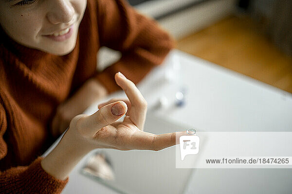 Boy holding contact lens on finger at home