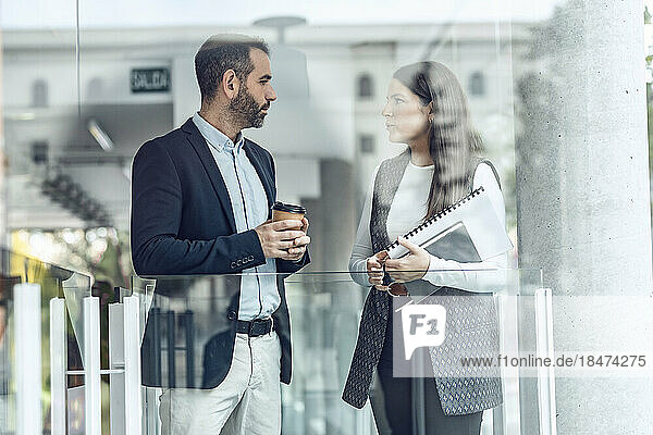 Businessman having discussion with colleague seen through glass