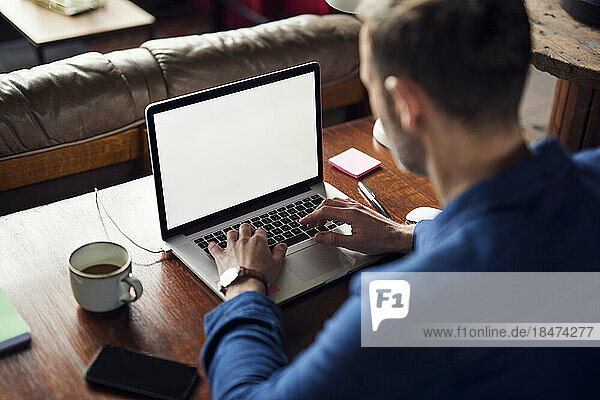 Freelancer working on laptop at desk in loft office