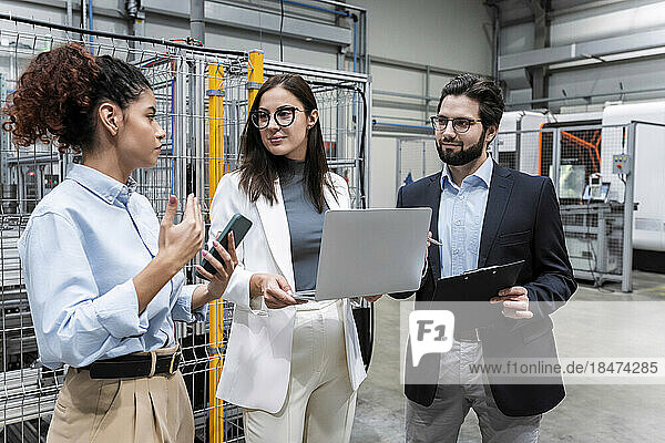 Businesswoman discussing with colleagues in factory
