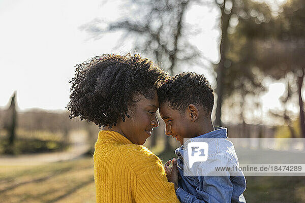 Mother and son touching foreheads in park