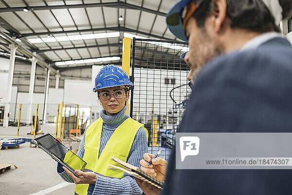 Engineer showing colleagues through tablet PC in factory