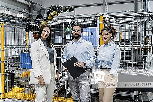 Smiling business people standing in factory