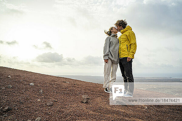 Affectionate young couple kissing each other standing on mountain