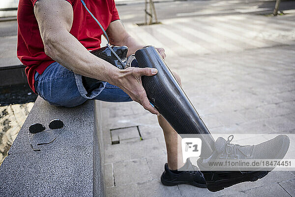 Man with disability adjusting prosthetic leg sitting on seat