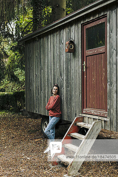 Lächelnde Frau stützte sich auf eine Holzhütte