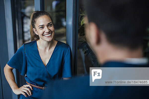 Smiling young businesswoman talking with colleague in office