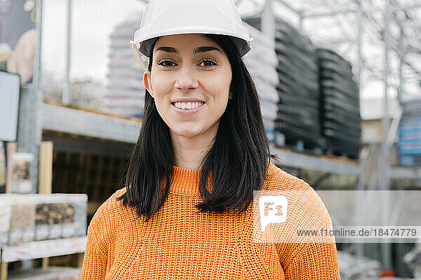 Smiling woman wearing hardhat at construction site