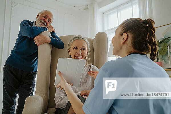 Nurse assisting senior patients through tablet PC at home