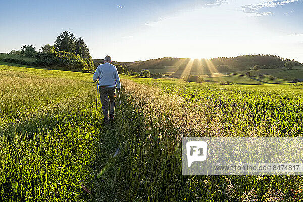 Active senior man walking in field at sunset