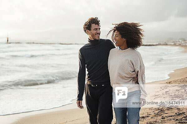 Fröhliches Paar geht gemeinsam am Strand spazieren