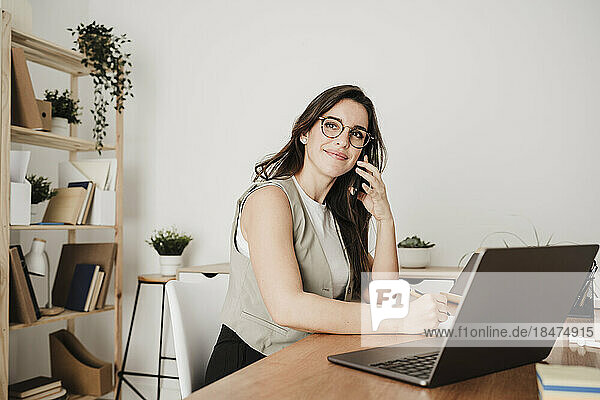 Lächelnde Geschäftsfrau  die im Büro über einen Laptop spricht