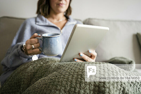 Woman using tablet PC on sofa at home