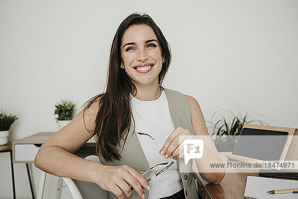 Happy businesswoman with eyeglasses at desk in office