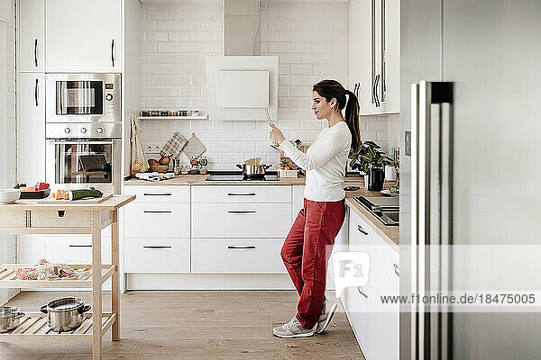 Woman using tablet PC standing in kitchen