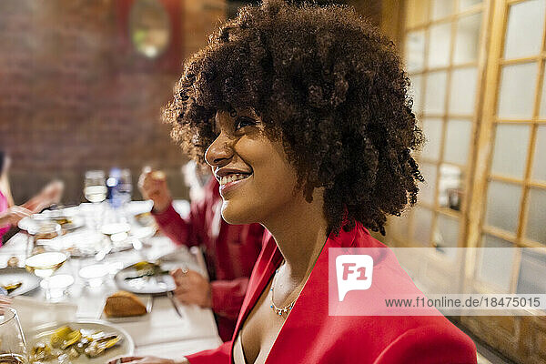 Happy woman with Afro hairstyle having dinner at restaurant