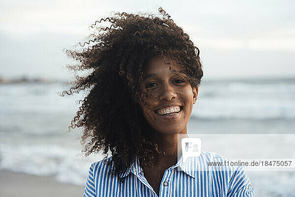 Happy young woman with curly hair at beach
