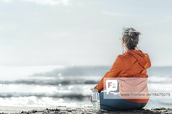 Woman sitting on beach at sunny day