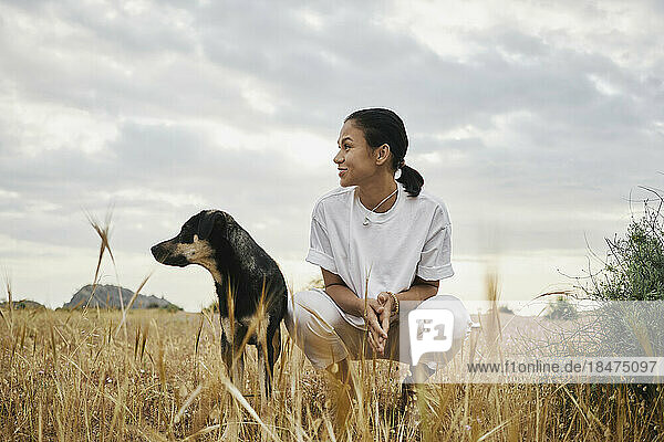 Smiling woman with dog at field
