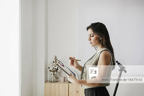 Businesswoman standing with clipboard in office