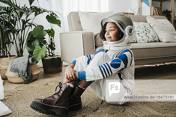 Thoughtful girl wearing space helmet at home