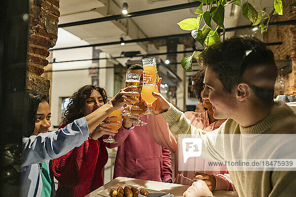 Happy friends toasting beer glasses at restaurant