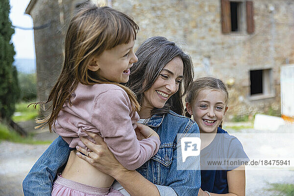 Happy mother enjoying with daughters in front of house