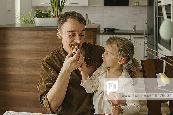 Daughter feeding pancakes to father at home