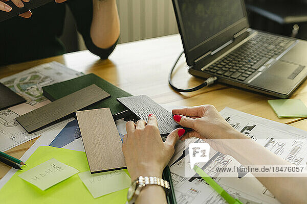 Close-up of two architects with samples  blueprint and laptop on table in office