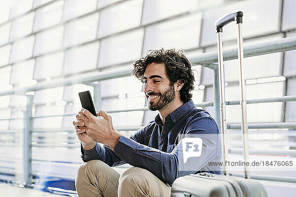Happy businessman using smart phone at station